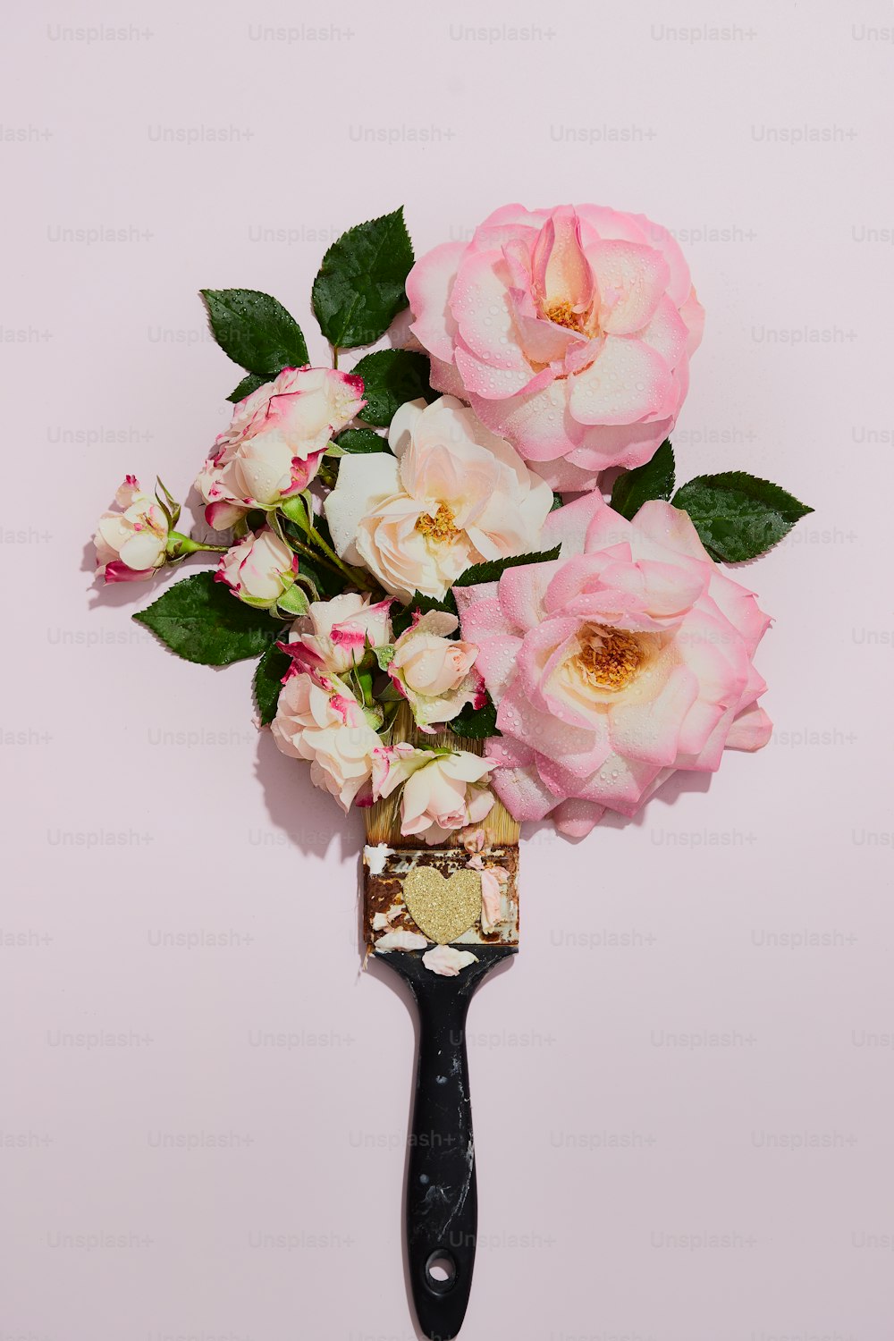 a bouquet of pink roses sitting on top of a hair brush