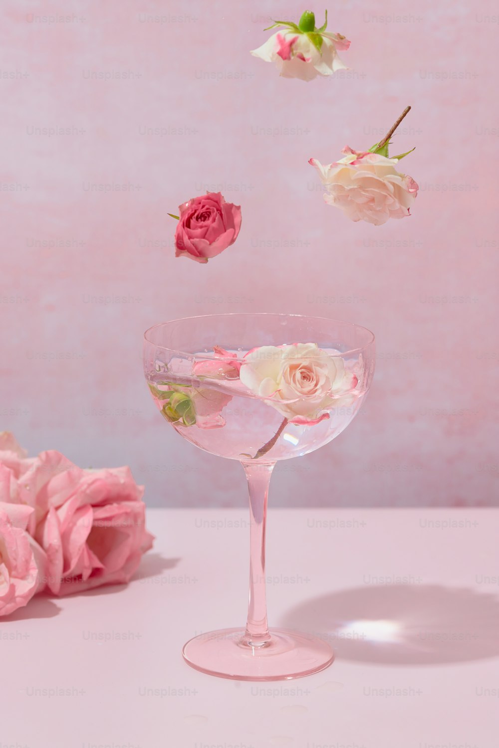 a glass filled with liquid and flowers floating in the air