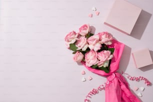 a bouquet of pink roses next to a white box