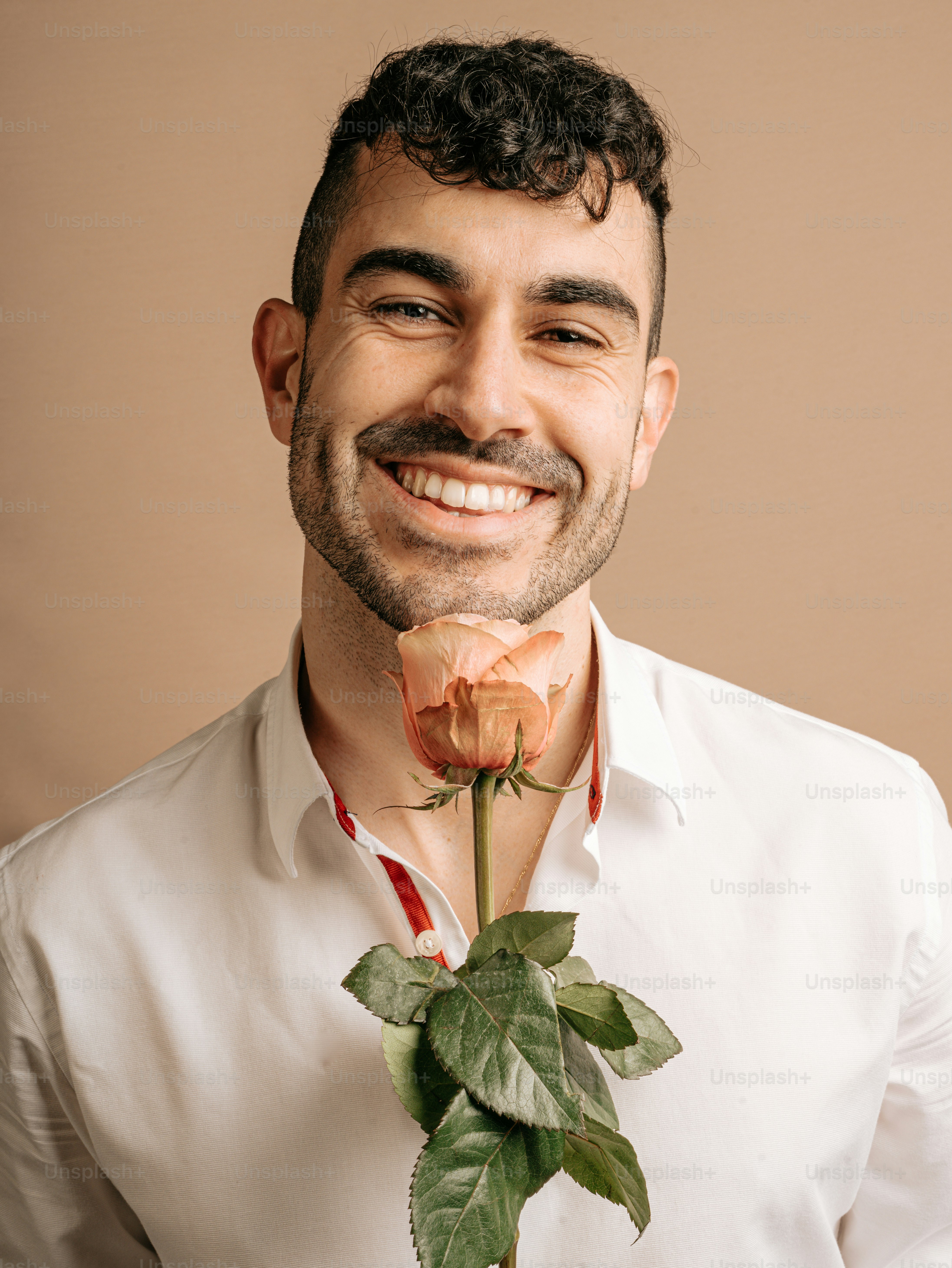 un hombre sonriente con una rosa en la mano