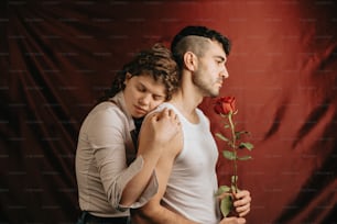 a man holding a woman while she holds a rose