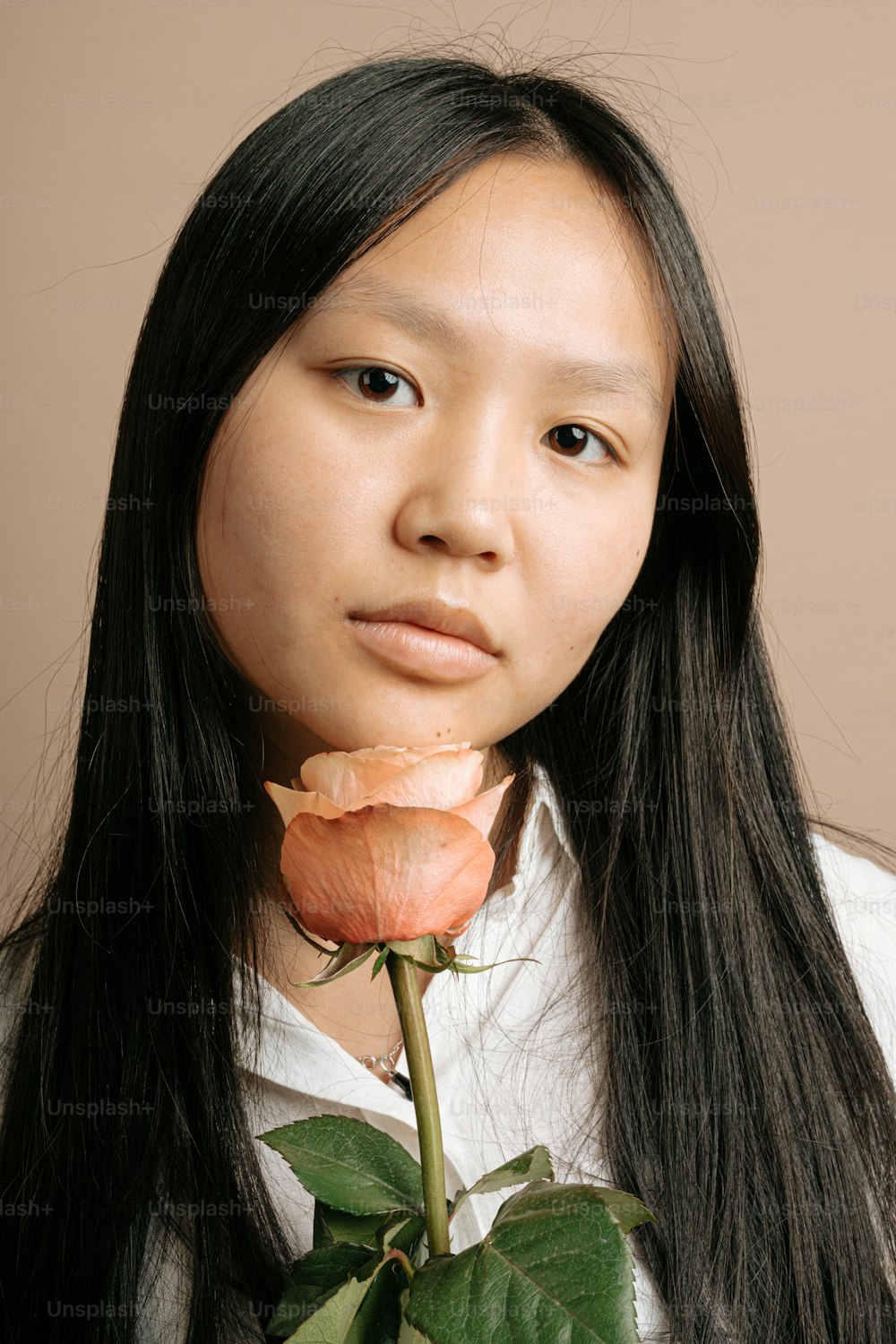 a woman with long black hair holding a rose