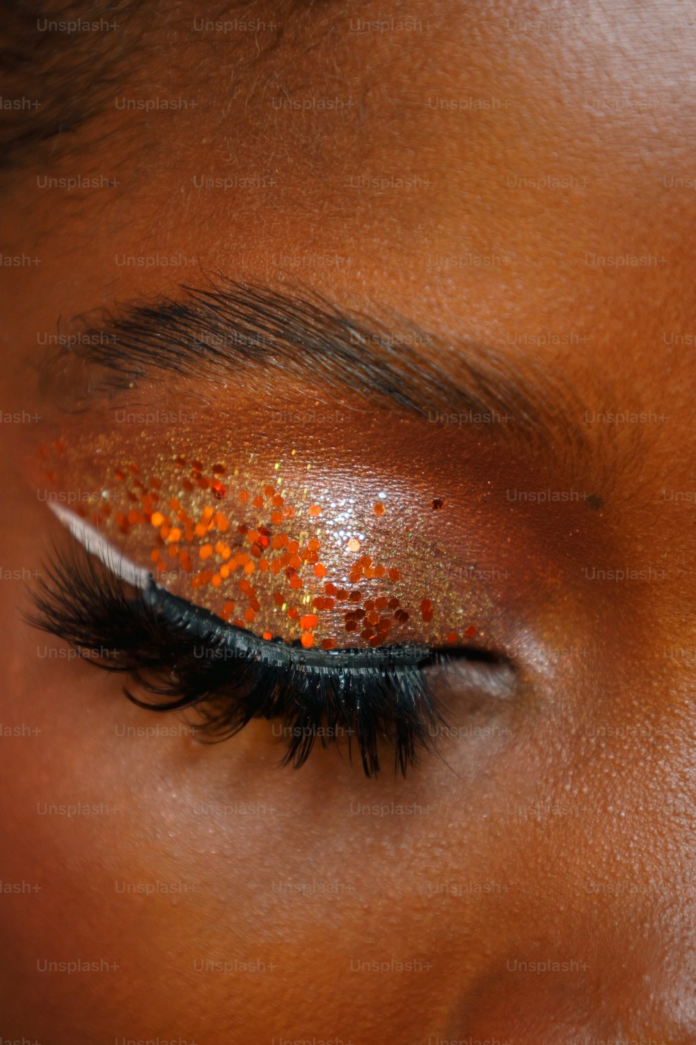 a close up of a woman's eye with orange glitter on it