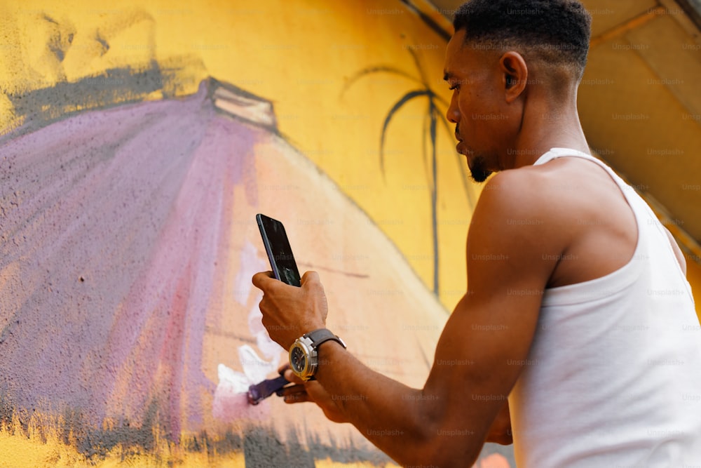 a man in a white tank top using a cell phone