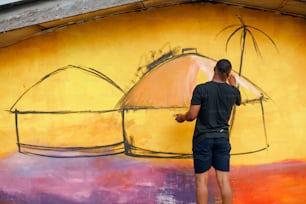 un homme debout devant une peinture murale