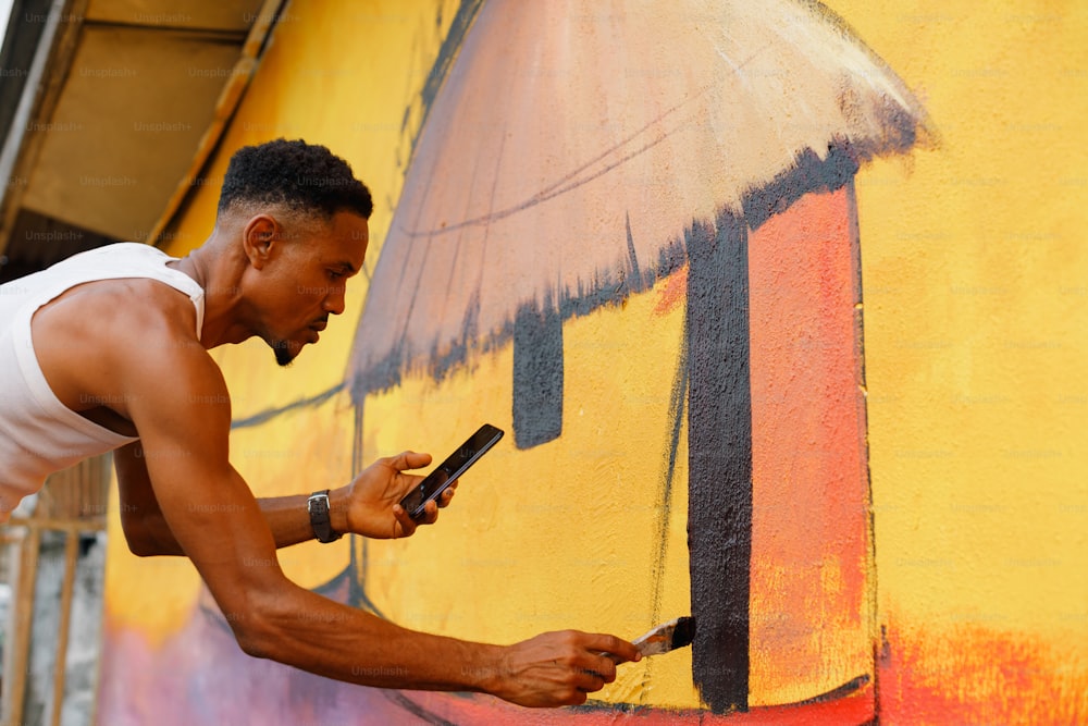 um homem está pintando uma parede com um telefone