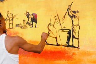 a man painting a mural on a yellow wall