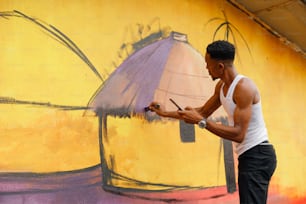 Um homem está pintando um mural na lateral de um prédio