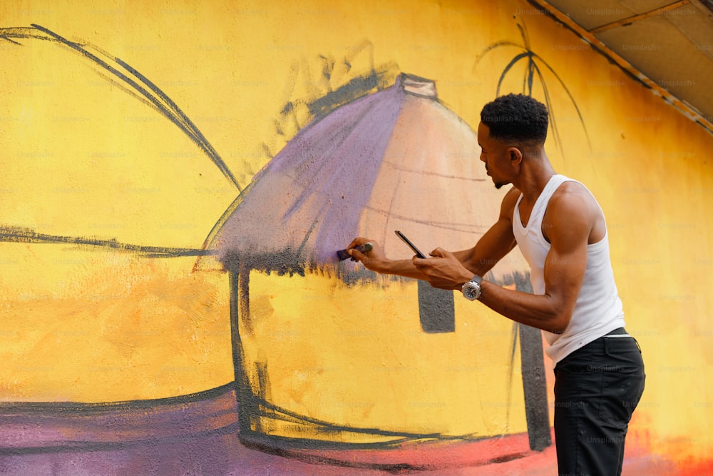 Um homem está pintando um mural na lateral de um prédio