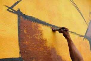 una persona che dipinge un muro con vernice gialla e marrone
