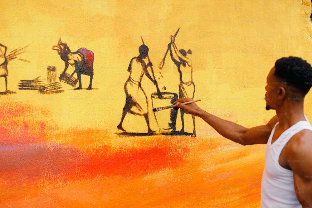 um homem pintando um mural na lateral de um prédio