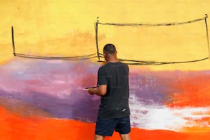 Un hombre parado frente a una pared con un teléfono celular en la mano
