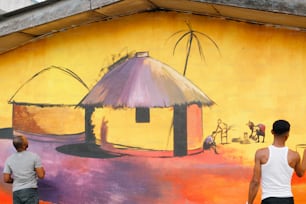 a couple of men standing next to a painting on the side of a building