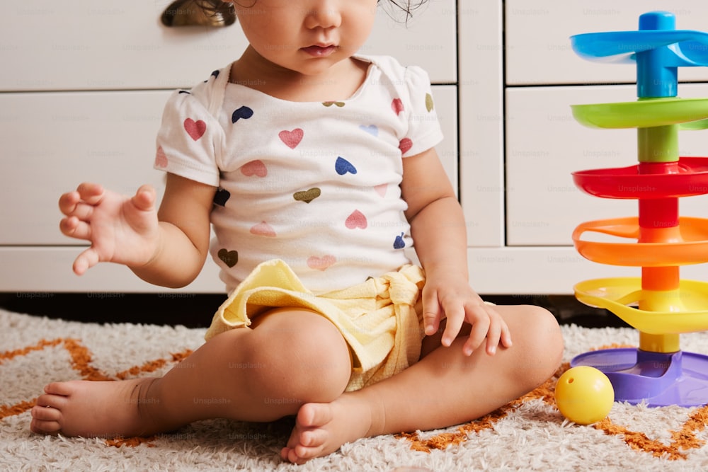 a baby sitting on the floor next to a stack of toys