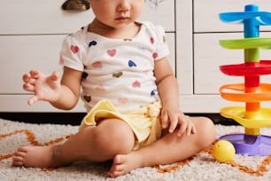 Un bebé sentado en el suelo junto a una pila de juguetes