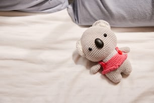 a crocheted teddy bear laying on a bed