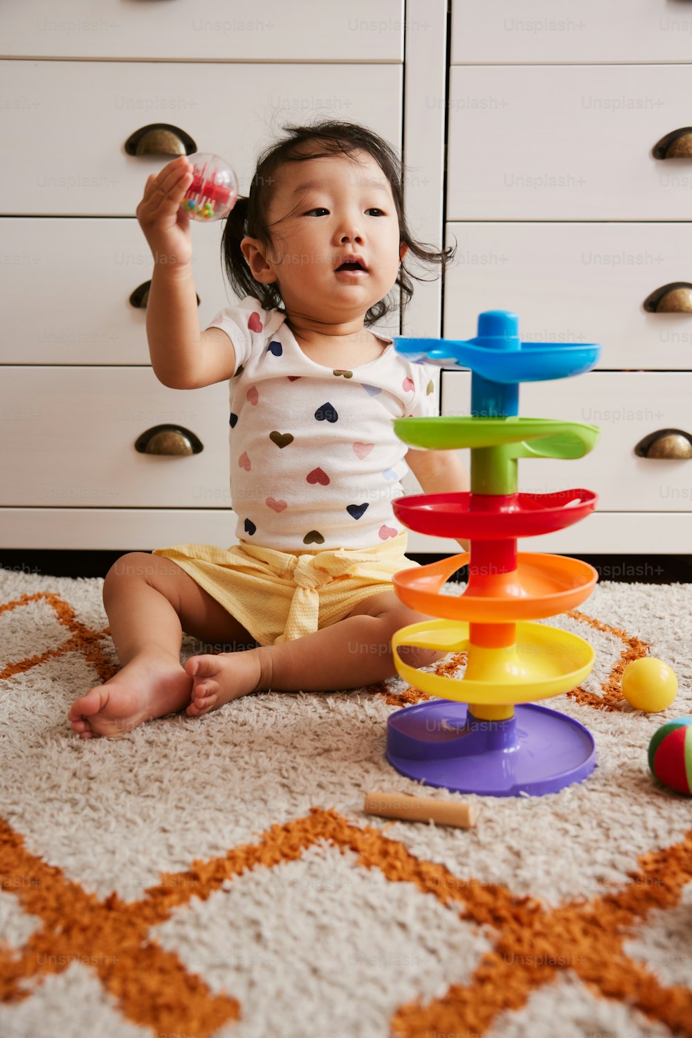 una bambina seduta sul pavimento che gioca con i giocattoli