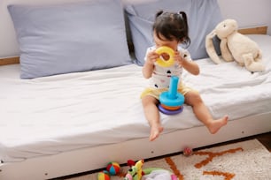 a little girl sitting on a bed playing with a toy