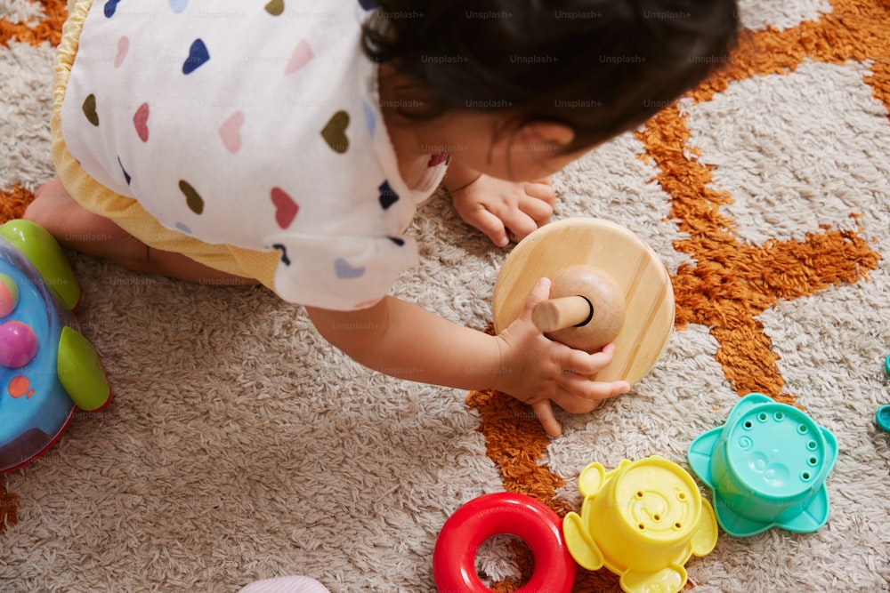 a baby playing with a wooden toy on the floor