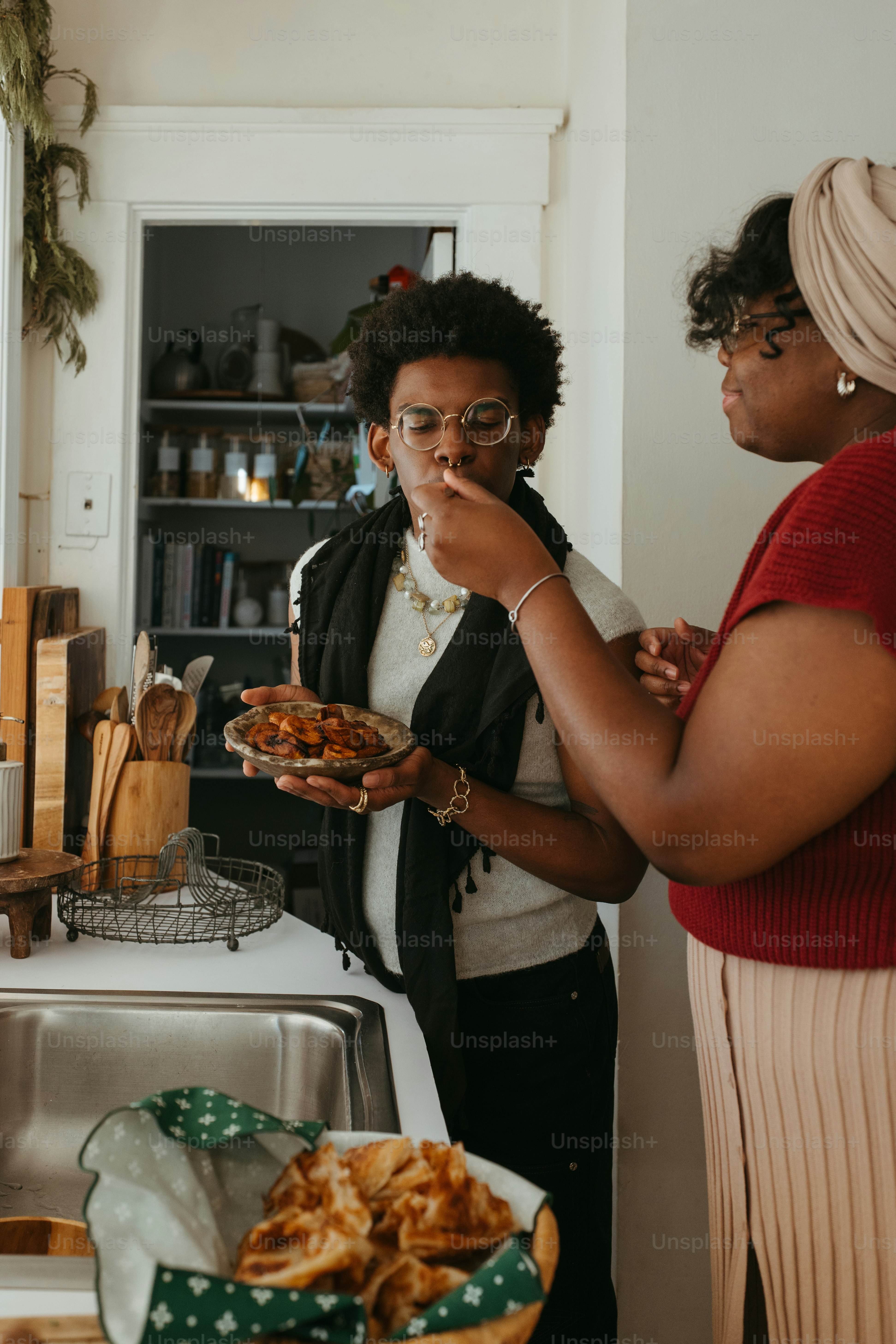 台所に立って料理を食べる二人の女性