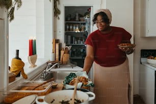 a woman standing in a kitchen holding a bowl of food