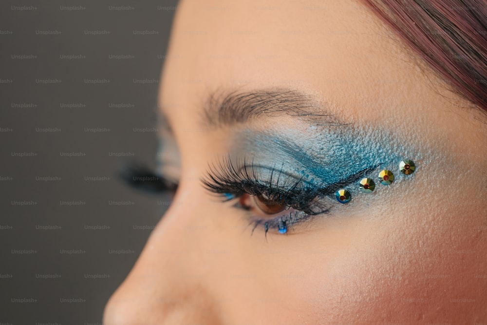 a close up of a woman's eye with blue and gold makeup