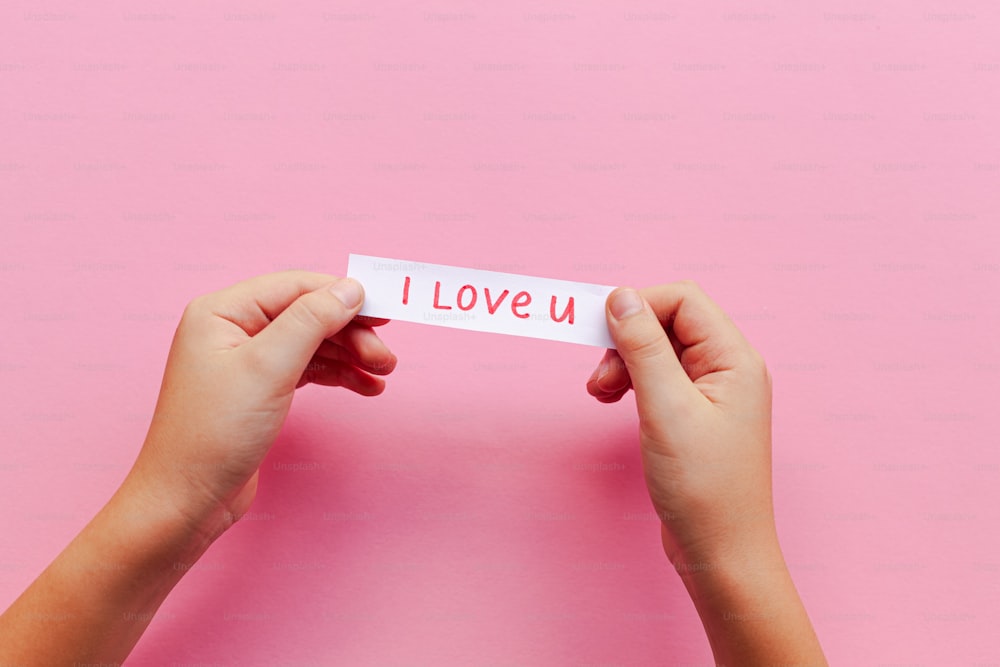Una persona che tiene in mano un pezzo di carta con la scritta "Ti amo"