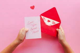 a person holding a red envelope with a card in it