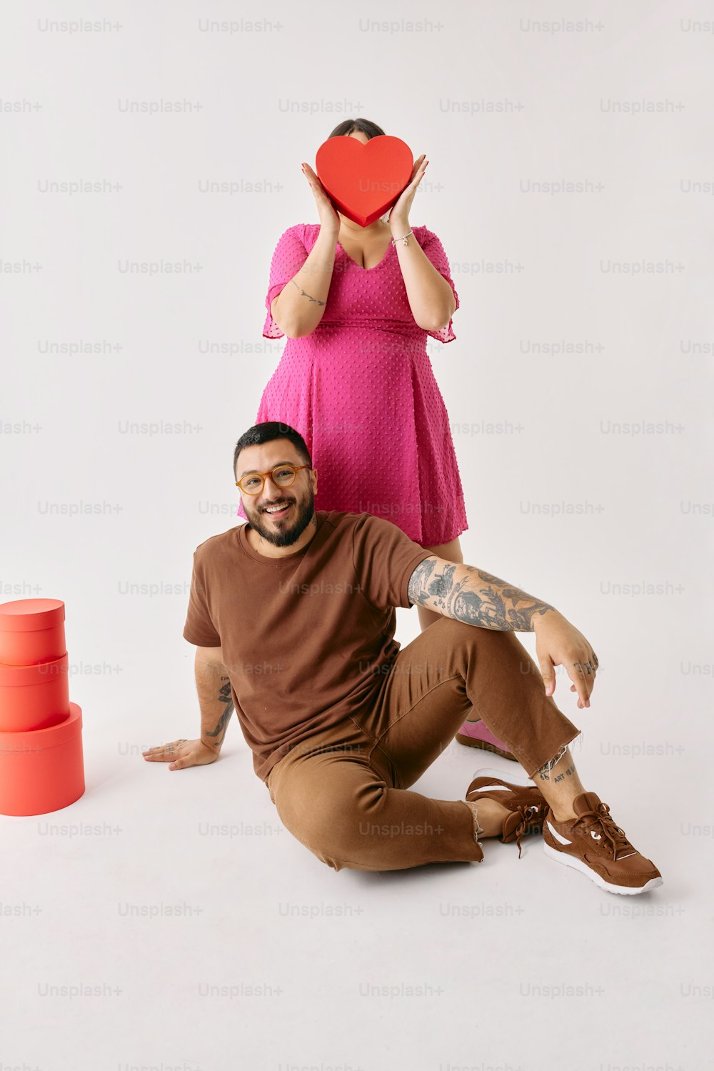 a man sitting on the ground next to a woman holding a heart