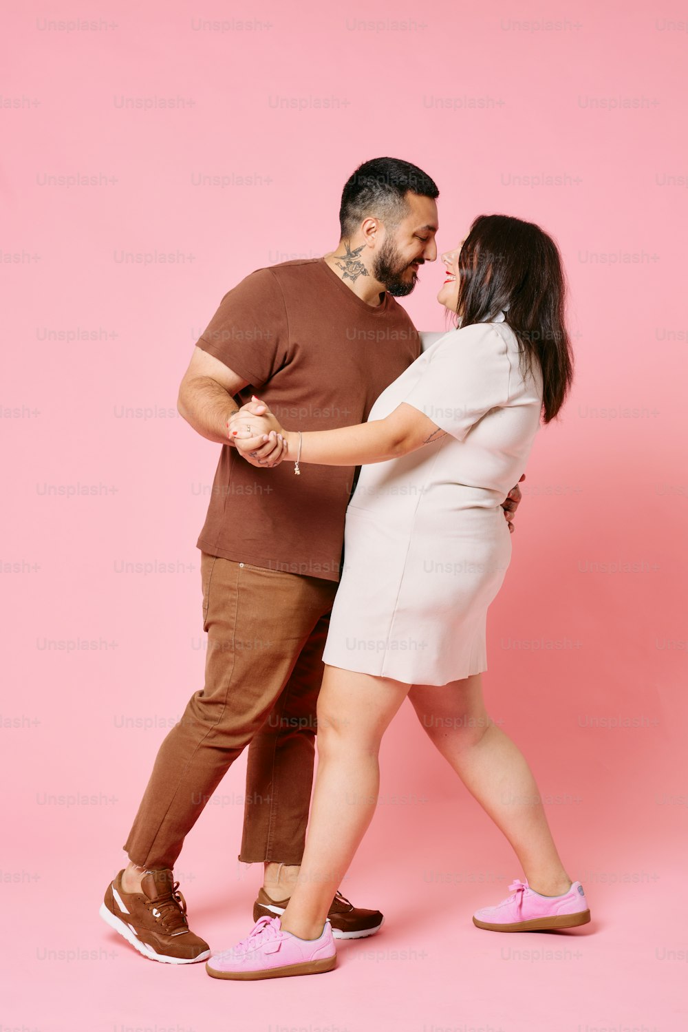 a man and a woman dancing together on a pink background