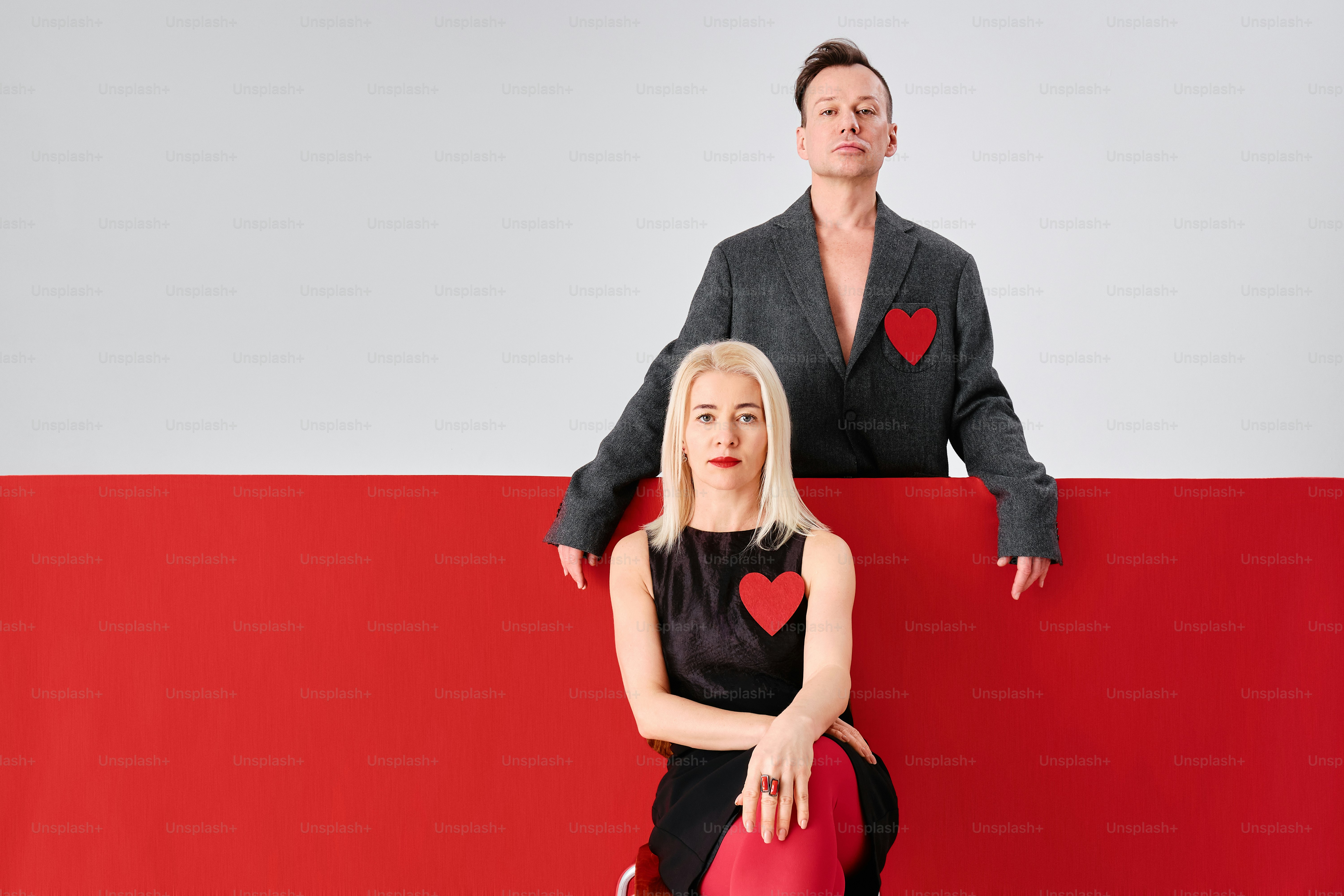 a woman sitting on top of a red and white wall next to a man