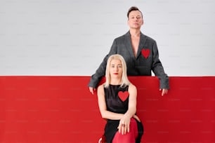 a woman sitting on top of a red and white wall next to a man