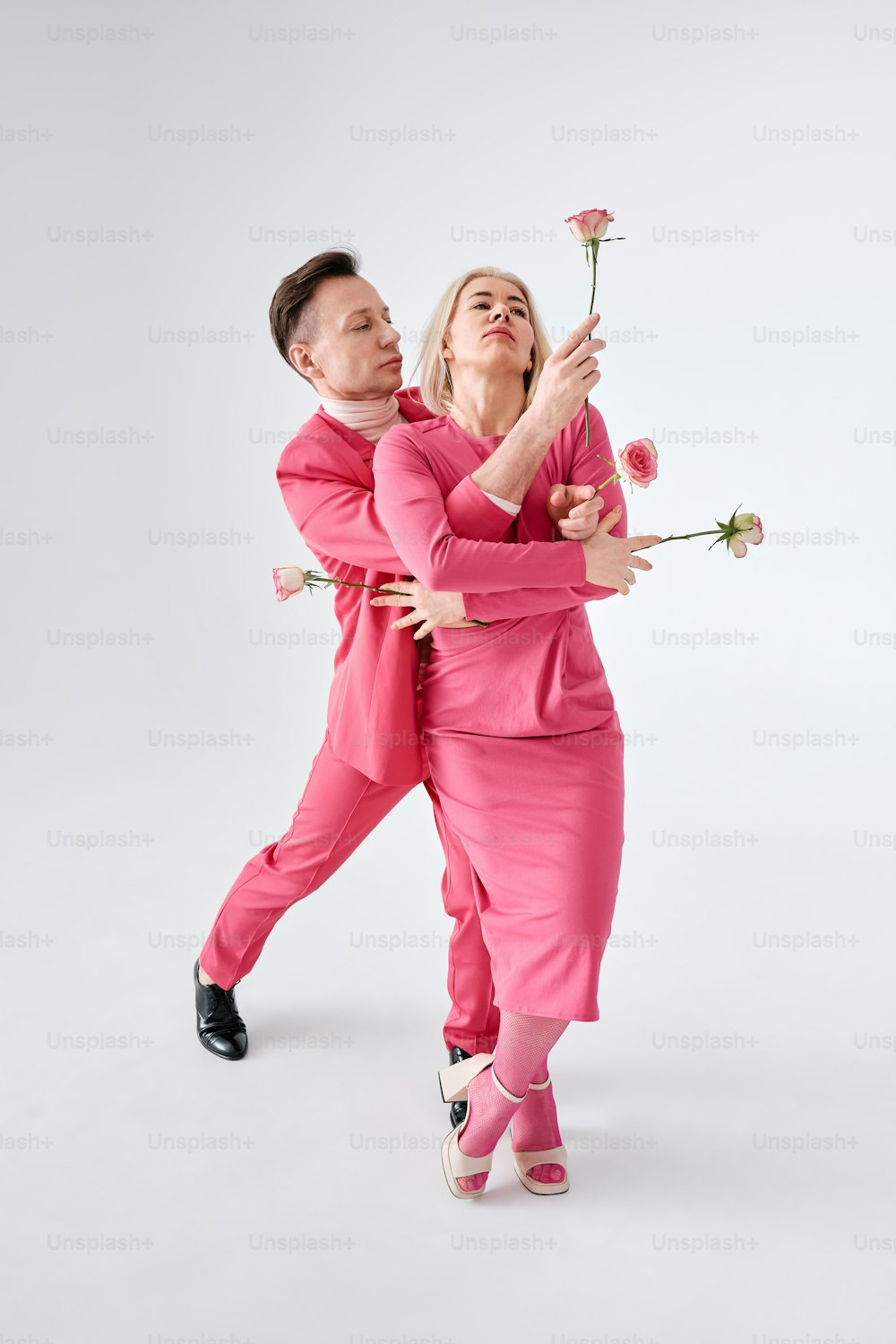 분홍색 옷을 입은 남자와 여자가 사진을 찍기 위해 포즈를 취하고 있다