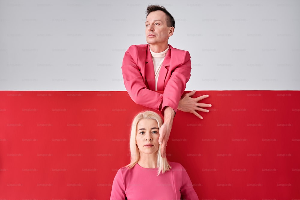 a woman standing next to a man on a red and white wall