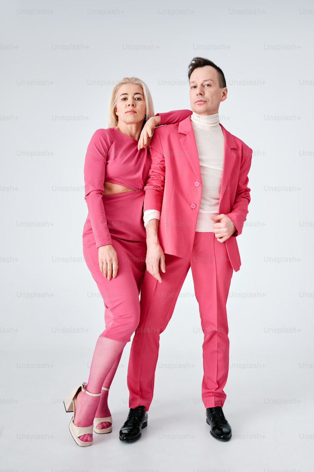un hombre con un traje rosa y una mujer con un top blanco