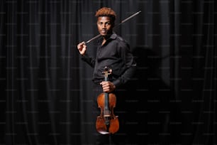 a man is holding a violin and posing for a picture
