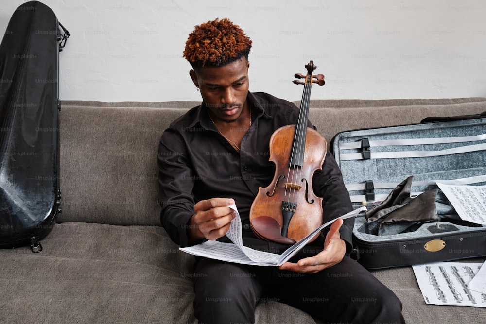 a man sitting on a couch holding a violin