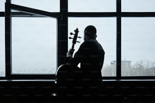 um homem segurando um violino em frente a uma janela