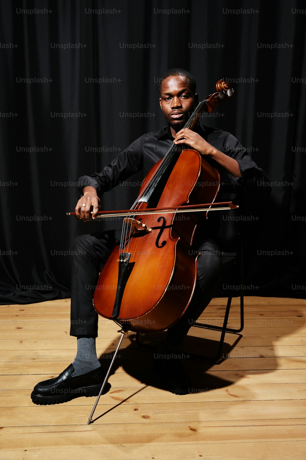 un uomo seduto su una sedia con in mano un violoncello
