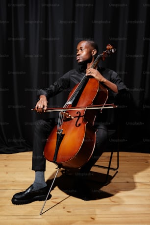 a man sitting in a chair holding a cello