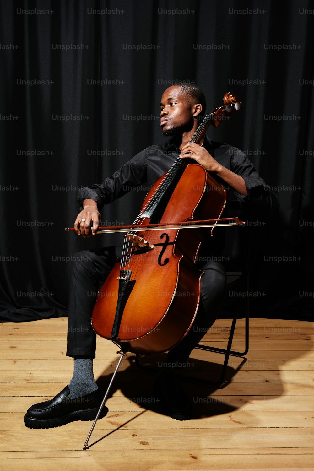 a man sitting in a chair holding a cello
