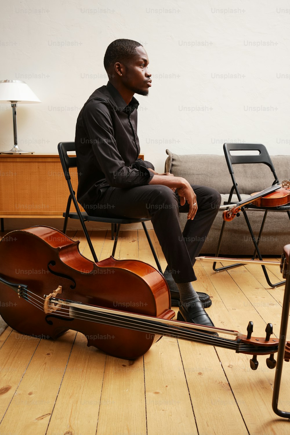 um homem sentado em uma cadeira ao lado de um violino