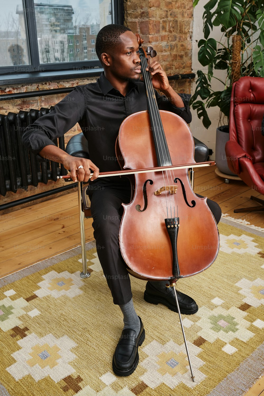 um homem sentado em uma cadeira segurando um violoncelo