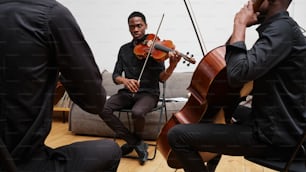 a man playing a violin while another man sits on a couch