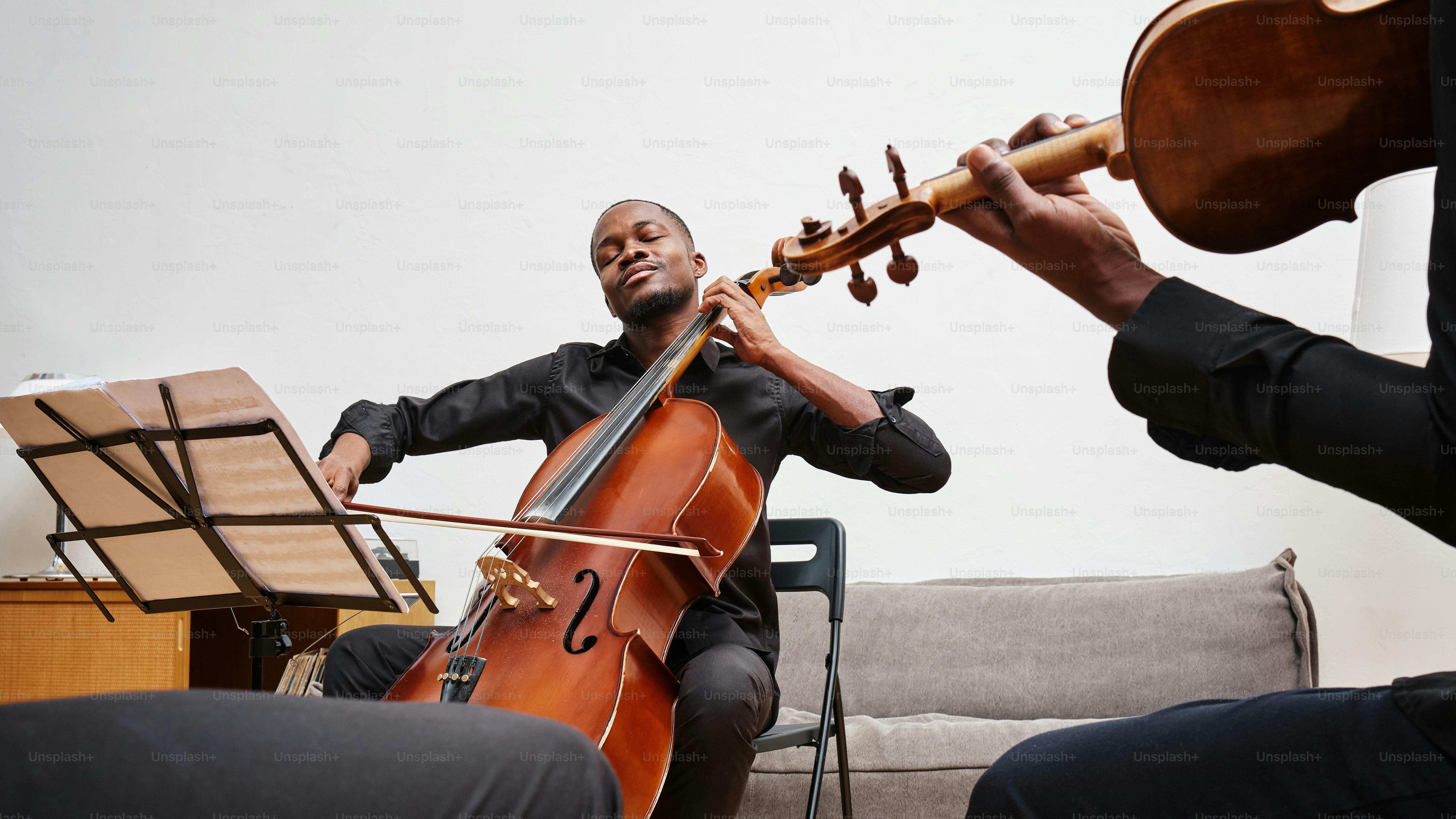 un uomo che suona un violino e un altro uomo seduto su un divano