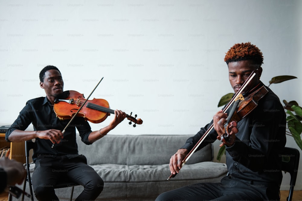 two men playing violin in a living room