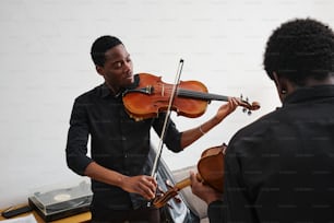 a man playing a violin while another man watches