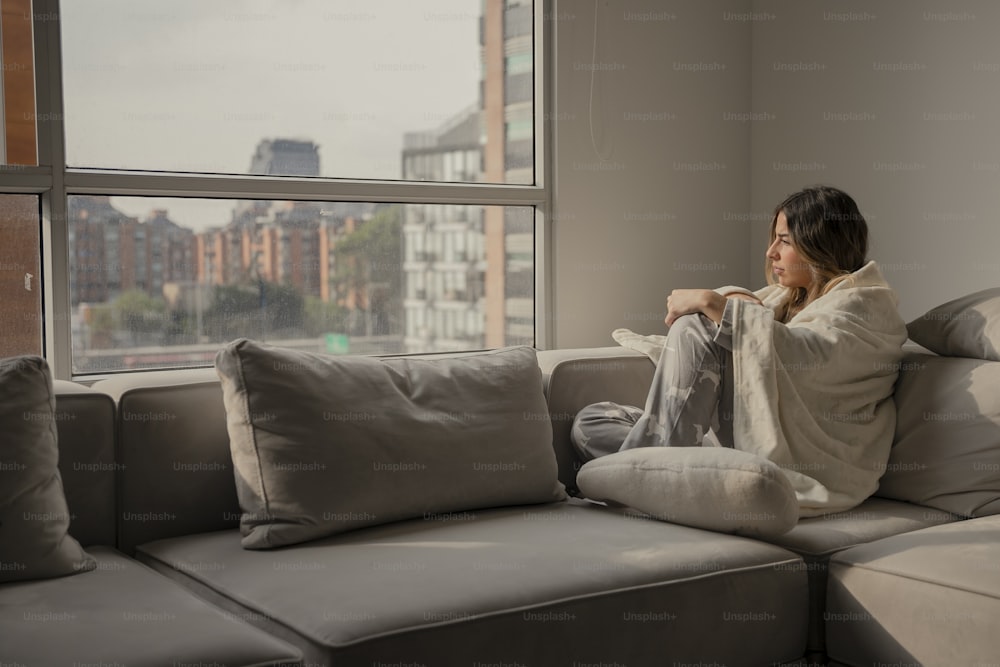 a woman sitting on a couch looking out a window