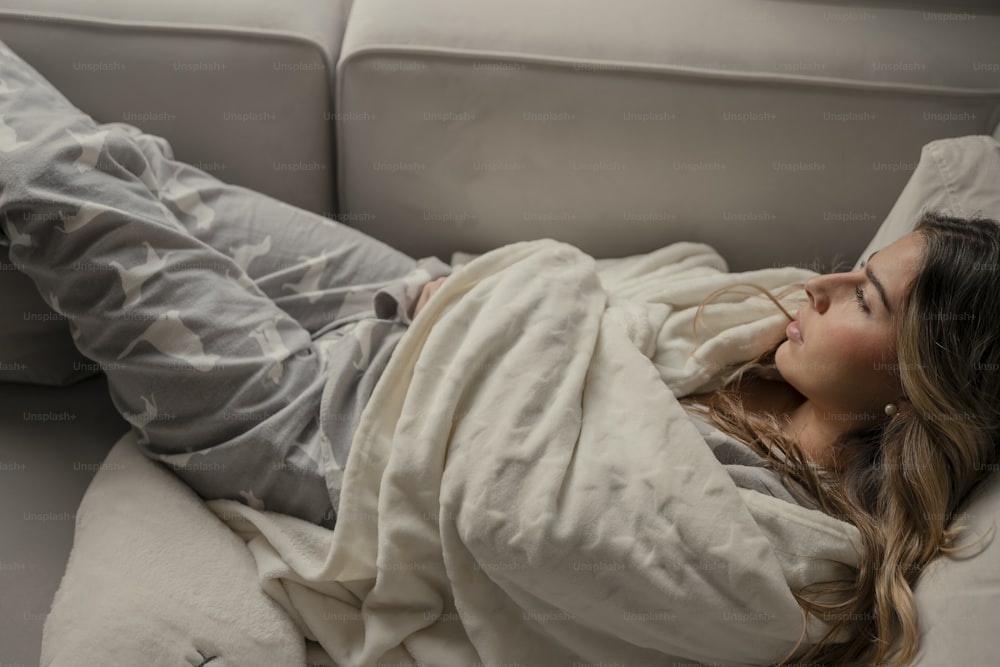 una donna sdraiata su un divano coperta da una coperta