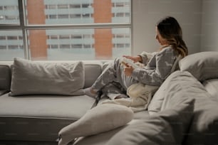 uma mulher sentada em um sofá segurando um controle remoto